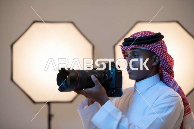 مصور سعودي يحمل كاميرا احترافية في استوديو تصوير