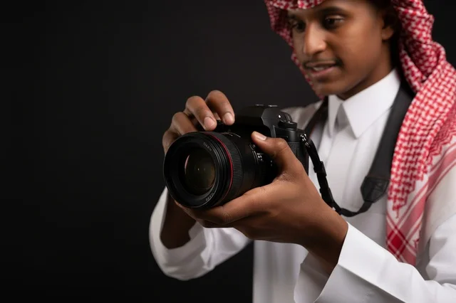 شاب سعودي بالزي التقليدي يمسك كاميرا تصوير احترافية