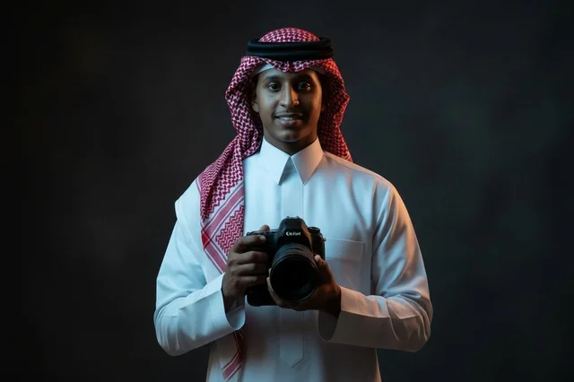 مصور سعودي يمسك كاميرا احترافية في الاستوديو