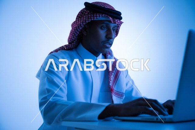 رجل سعودي يعمل على الكمبيوتر المحمول بإضاءة زرقاء