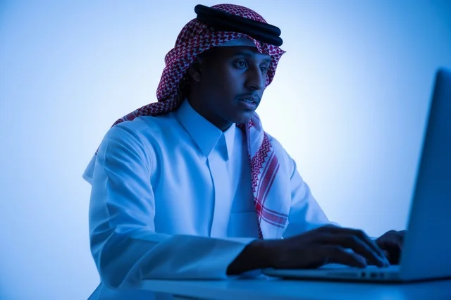 Saudi Man Working on Laptop in Blue Light Studio