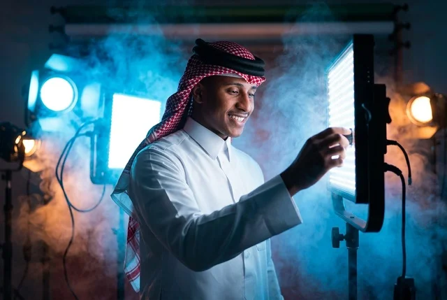 شاب سعودي يضبط لوحة إضاءة الاستوديو الاحترافية
