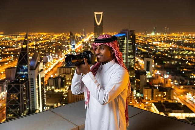 مصور سعودي بالزي التقليدي يطل على أفق الرياض ليلاً
