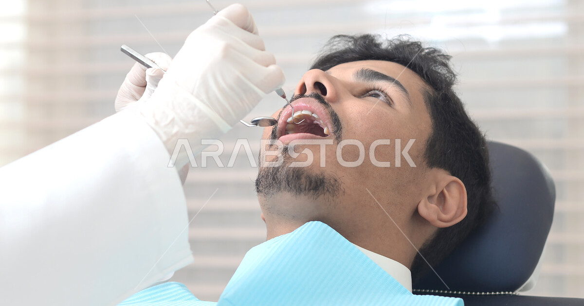 A Saudi Arabian Gulf man visiting the dentist, examining and diagnosing