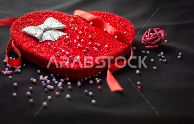 صورة مقربة لعلبة على شكل قلب أحمر كبير مع شريط أحمر مصورة على خلفية سوداء ، هدية عيد الميلاد ، يوم الحب ، إكسسوارات الهدايا ، أعياد ومناسبات ، فالنتاين ، مناسبات سعيدة