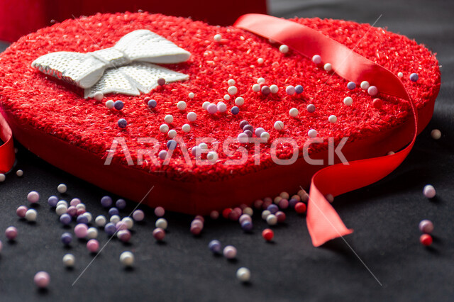 صورة مقربة لعلبة على شكل قلب أحمر كبير مع شريط أحمر مصورة على خلفية سوداء ، هدية عيد الميلاد ، يوم الحب ، إكسسوارات الهدايا ، أعياد ومناسبات ، فالنتاين ، مناسبات سعيدة