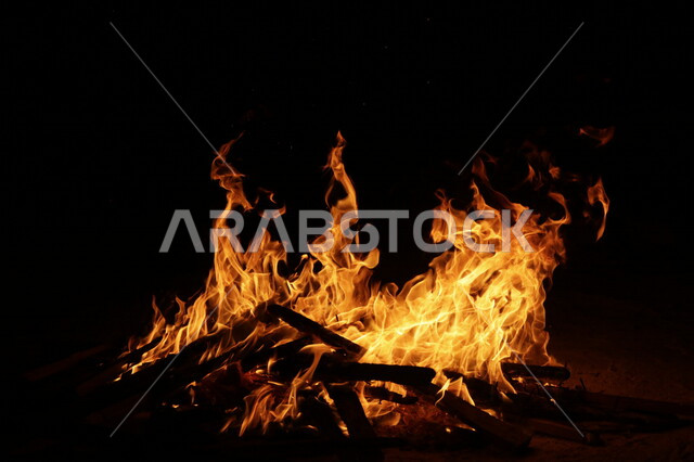 النيران المشتعلة في الحطب ليلاً ، اللهب الأحمر المشتعل في رحلة تخييم بالصحراء ، جمال الطبيعة في صحراء المملكة العربية السعودية ليلاً ، البر و التخييم