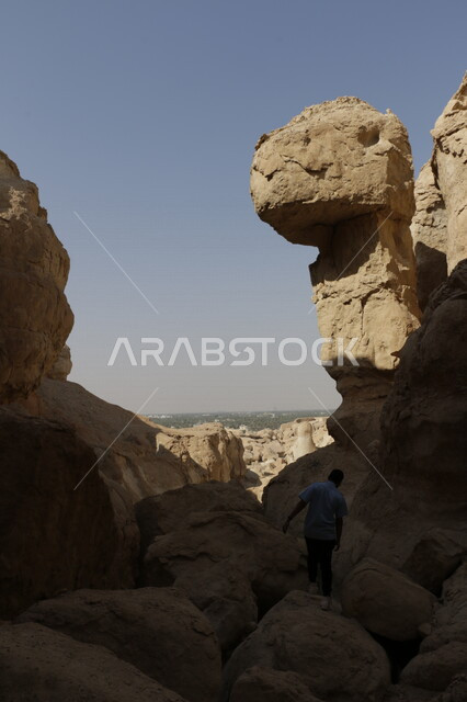 صورة من الخلف لرجل يقوم بتسلق الصخور الجبلية ، مغامرات التسلق على التشكيلات الصخرية في الجبال ، مناطق طبيعية سياحية في المملكة العربية السعودية
