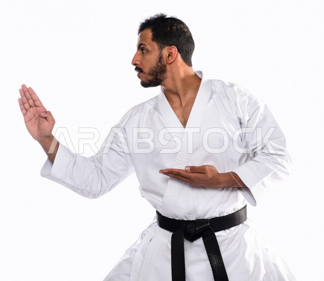 Portrait of a Saudi Arabian Gulf man practicing Japanese karate, white karate uniform with black belt, training in special combat movements, Japanese martial arts, martial arts, physical strength, kata movements, white background