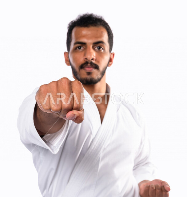 Portrait of a Saudi Arabian Gulf man practicing Japanese karate, white karate uniform with black belt, training in special combat movements, Japanese martial arts, martial arts, physical strength, kata movements, white background
