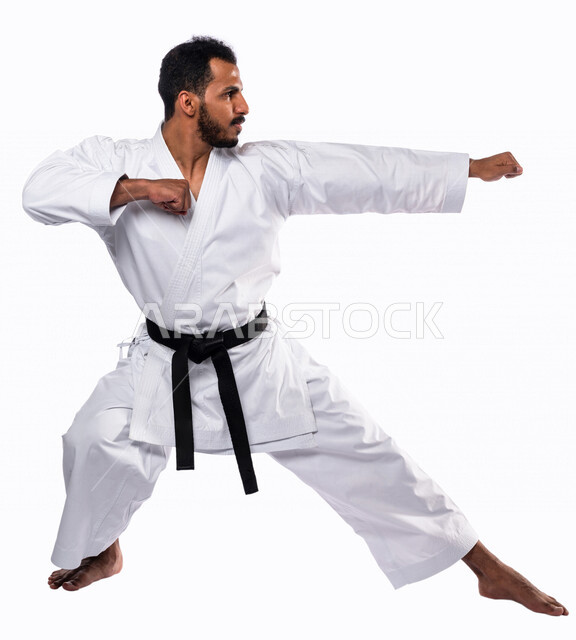 Portrait of a Saudi Arabian Gulf man practicing Japanese karate, white karate uniform with black belt, training in special combat movements, Japanese martial arts, martial arts, physical strength, application of kata movements, white background, full-leng