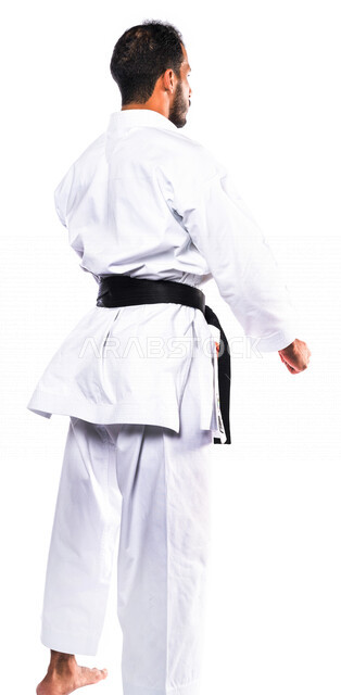 بورتريه من الخلف لرجل عربي خليجي سعودي يمارس رياضة الكاراتيه اليابانية، زي الكاراتيه الأبيض مع الحزام الأسود، التدرب على حركات قتالية خاصة، فنون قتالية يابانية، فنون الدفاع عن النفس، القوة البدنية، تطبيق حركات الكاتا، خلفية بيضاء، صورة الجسم بالكامل