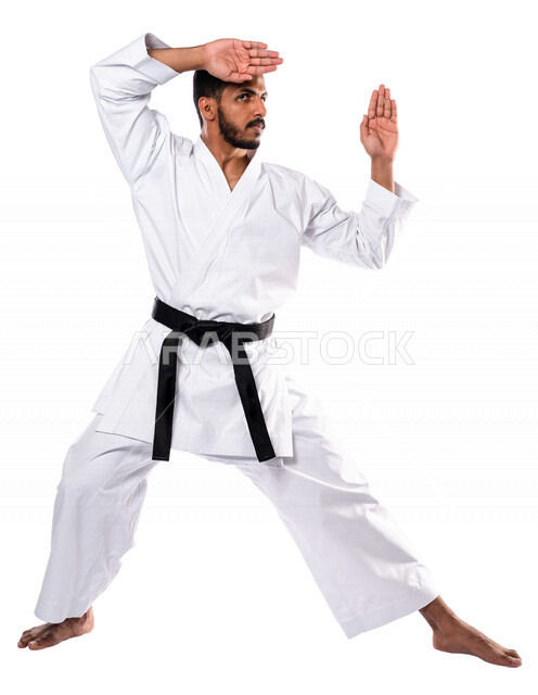 بورتريه لرجل عربي خليجي سعودي يمارس رياضة الكاراتيه اليابانية، زي الكاراتيه الأبيض مع الحزام الأسود، التدرب على حركات قتالية خاصة، فنون قتالية يابانية، فنون الدفاع عن النفس، القوة البدنية، تطبيق حركات الكاتا، خلفية بيضاء، صورة الجسم بالطول الكامل