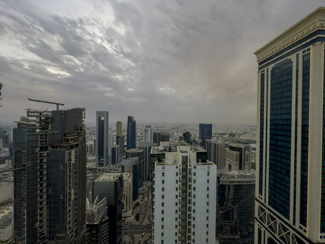  Elevated panoramic view of Doha city with modern skyscrapers in West Bay district and a main road leading towards Doha Corniche and the Arabian Gulf under a partly cloudy sky, Doha, Qatar