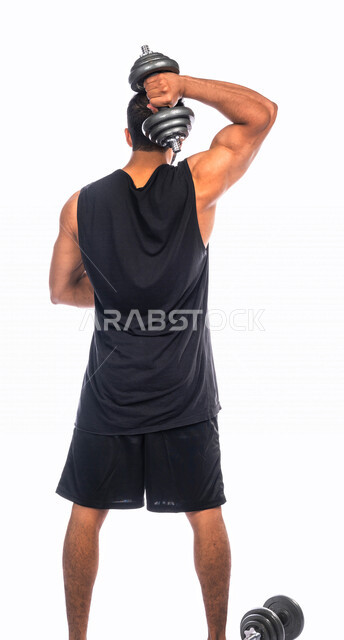 بورتريه من الخلف لشاب عربي خليجي سعودي يقوم بممارسة التمارين الرياضية مع الدمبل ، نشاط بدني للمحافظة على الصحة و اللياقة الجسدية ، تقوية عضلات الجسم و بنائها ، تمارين رفع الأثقال (دمبلز)، رفع الأوزان الحديدية الثقيلة ، كمال الأجسام ، لياقة و رشاقة