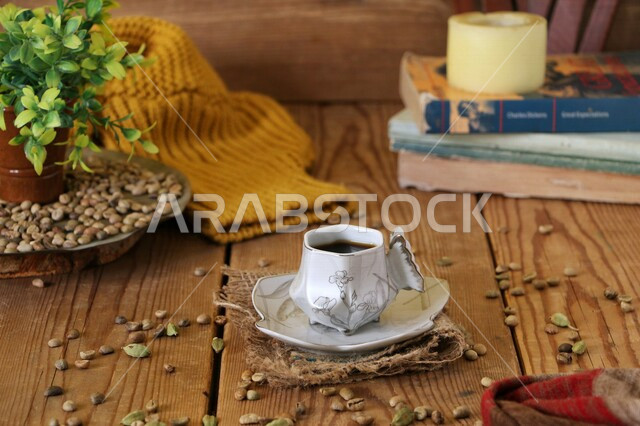 فنجان القهوة الساخنة على طاولة خشبية عليها حبوب البن و حبوب الهان المتناثرة ، مشروب القهوة الساخن ، قهوة اسبريسو ، مشروبات ساخنة لذيذة ، قهوة داكنة 