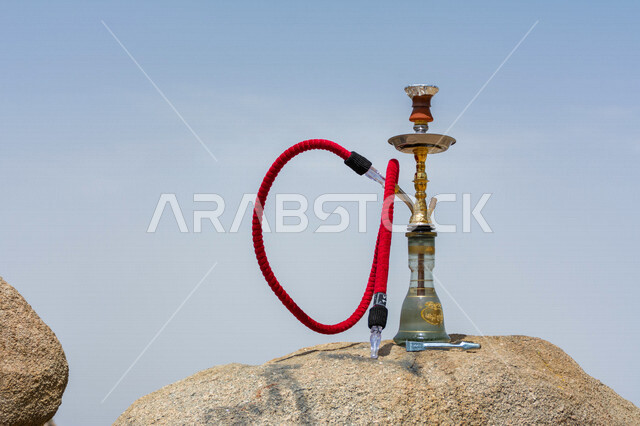صورة لشيشة موضوعة على الصخرة  ، أرجيلة تحتوي على خرطوم ووعاء الماء ، البر والتخييم ، نزهات وترفيه ، تلوث البيئة ، الشيشة والدخان 