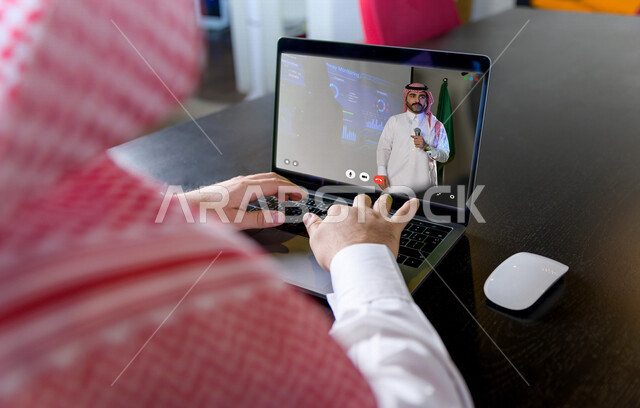 رجل عربي خليجي سعودي يقوم باجراءة مكالمة فيديو من خلال الحاسوب المحمول، اجتماع عمل عن بعد من خلال الحاسوب المحمول، تنظيم وادارة الأعمال عبر الجهاز التقني، تقنيات حديثة، دردشة وتواصل، علاقات اجتماعية
