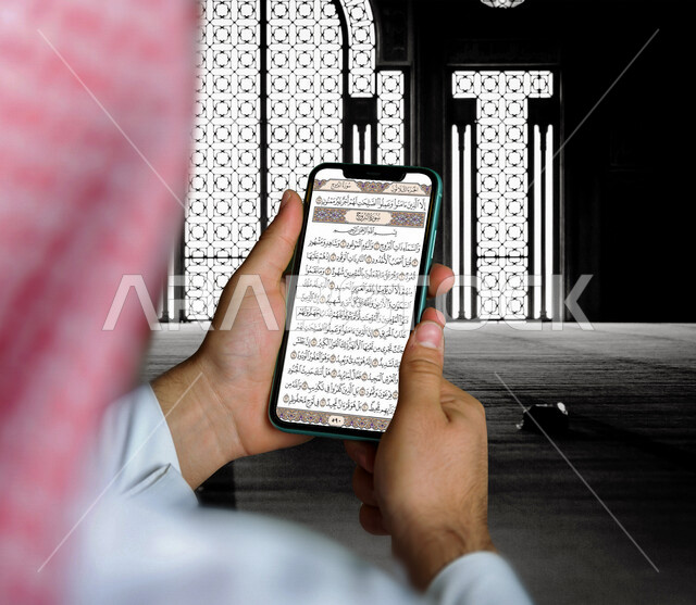 رجل عربي خليجي سعودي يقرأ القران الكريم من خلال الهاتف المحمول، قراءة القران، خدمة تطبيق القرآن الكريم  على الجوال، استخدام التقنيات الحديثة في العبادة والتقرب الى الله، استخدام تقنيات حديثة، تطبيقات اسلامية