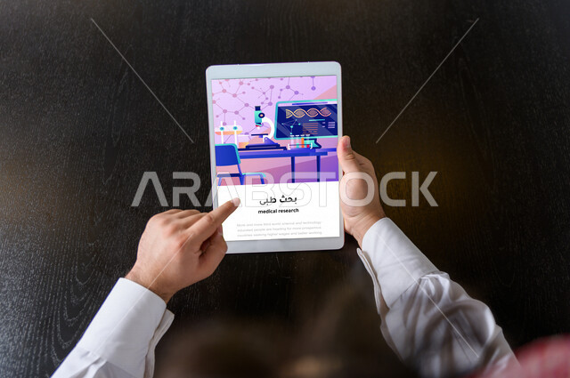 Close-up of the hand of a Saudi Arabian Gulf man using an iPad technical device, using a medical application on the Internet, medical advice, searching for medical information