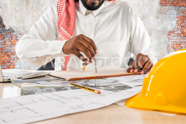 A Saudi Arabian Gulf engineer inside an engineering office, using an engineering caliper, using a laptop computer to follow up on engineering work and tasks, using engineering tools and equipment, an engineering design scheme, professions and jobs, a prof