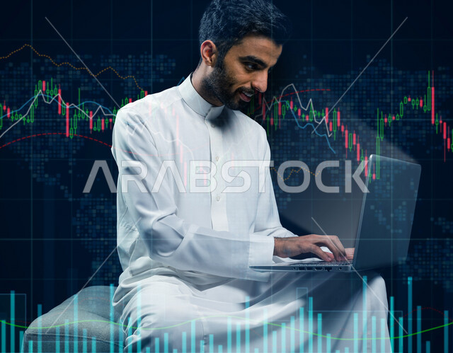 رجل عربي خليجي سعودي مبتسم يقوم بإستخدام الحاسوب المحمول مع خلفية مدموجة بمجموعة من الرسومات البيانية للبورصة المالية ، متابعة سوق الاوراق المالية ، النجاح في التداول المالي ، مراقبة الاقتصاد والمعلومات المالية ، الاستثمار المالي 