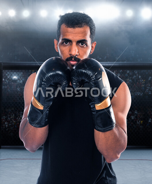 شاب عربي خليجي سعودي في النادي، يرتدي زي الملاكمة وقفازات الملاكمة، التدرب على حركات قتالية، فنون قتالية، رياضات القتال والدفاع عن النفس، الملاكمة والمصارعة، رياضة الملاكمة في السعودية، نادي رياضي رجالي، بطولات رياضة الملاكمة الرجالية