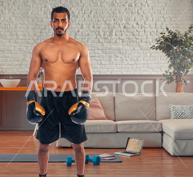 شاب عربي خليجي سعودي، يرتدي زي الملاكمة وقفازات الملاكمة، التدرب على حركات قتالية، فنون قتالية، رياضات القتال والدفاع عن النفس، الملاكمة والمصارعة، رياضة الملاكمة في السعودية، نادي رياضي رجالي، بطولات رياضة الملاكمة الرجالية