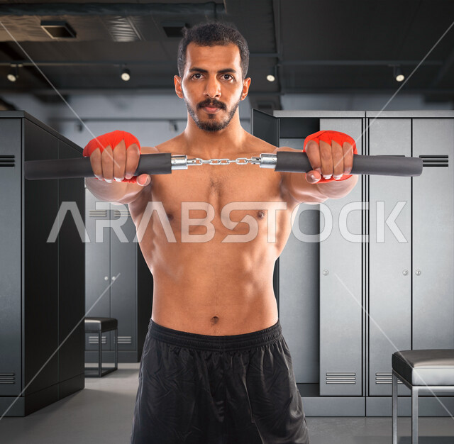 شاب عربي خليجي سعودي في النادي الرياضي ، يحمل بيده سلاح الننشاكو ( بروس لي) ، التدرب على حركات قتالية ، نشاط وحركة ، فنون قتال يابانية، الدفاع عن النفس، القوة والثقة ، مفهوم رياضات الألعاب الأولمبية ، عصا بروسلي ، ألعاب الكونغ فو