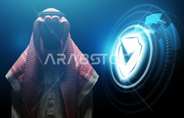 رجل عربي خليجي سعودي يعمل في الأمن السيبراني ، أيقونة نظام الحمايه و الأمان مضيئة بتقنية الهولوجرام ثلاثية الأبعاد، الحفاظ على البيانات الشخصية للمستخدمين, الدخول الامن، مفهوم أمن تكنولوجيا المعلومات