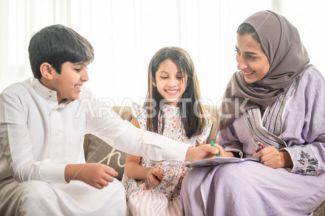 ام عربية خليجية سعودية تقوم بتعليم ابنائها، الانشطة التعليمية، تنمية قدرات الطفل، تعلم وتطور الاطفال، تعليم وتطوير الابناء، رعاية الابناء، الاهتمام بتعليم الابناء