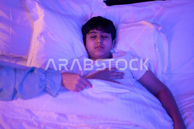 طفل عربي خليجي سعودي نائم، النوم الصحي للاطفال، وقت النوم، النوم المبكر، وسادة بيضاء ناعمة، الاسترخاء والاستمتاع بنوم هادئ وصحي
