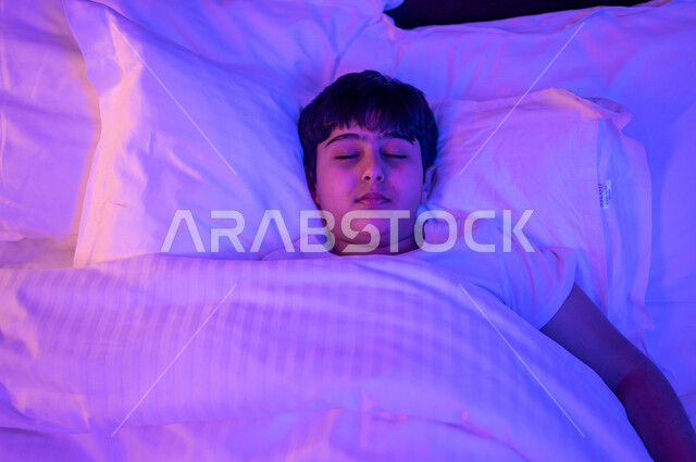 طفل عربي خليجي سعودي نائم، النوم الصحي للاطفال، وقت النوم، النوم المبكر، وسادة بيضاء ناعمة، الاسترخاء والاستمتاع بنوم هادئ وصحي