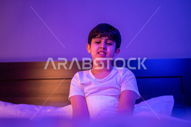 طفل عربي خليجي سعودي يستعد للنوم، ايماءات وجه ويدين تدل على النعس الشديد، الاسترخاء قبل النوم