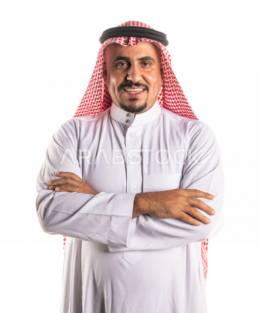 بورتريه لرجل عربي خليجي سعودي يقف مكتف اليدين بسعادة وفرح ، رجل اعمال سعودي يرتدي الزي الخليجي التقليدي ، ايماءات الوجه واليدين تدل على الثقة بالنفس ، خلفية بيضاء