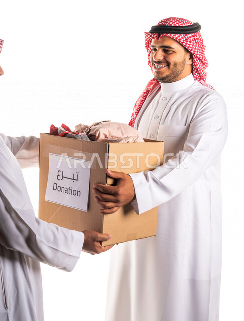 بورتريه لمتطوع عربي خليجي سعودي مبتسم وسعيد يقدم سلة خيرية لاسرة سعودية متعففة ، توزيع ملابس العيد ، اعمال خيرية ، تبرعات وعطاءات ، جمعيات خيرية للمحتاجين ، مبادرات انسانية ، شهر رمضان