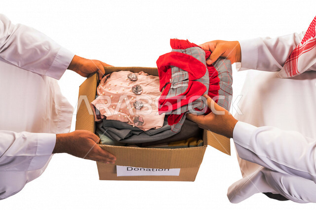 رجلان عربيان خليجيان سعوديان يتشاركان في تجهيز طرد الملابس للمحتاجين ، متطوعين لجمع التبرعات ، مشاريع وجمعيات خيرية ، عطاءات وتبرعات ، خدمة المجتمع السعودي المتعفف ، مؤسسة خيرية في المملكة العربية السعودية