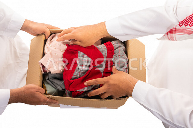 رجلان عربيان خليجيان سعوديان يتشاركان في تجهيز طرد الملابس للمحتاجين ، متطوعين لجمع التبرعات ، مشاريع وجمعيات خيرية ، عطاءات وتبرعات ، خدمة المجتمع السعودي المتعفف ، مؤسسة خيرية في المملكة العربية السعودية