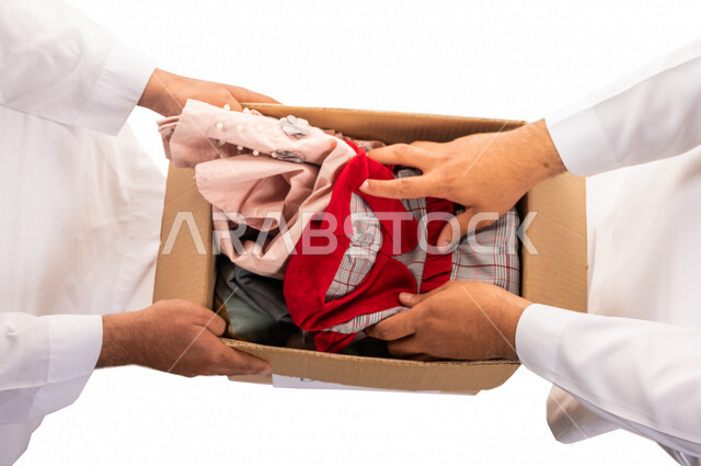 رجلان عربيان خليجيان سعوديان يتشاركان في تجهيز طرد الملابس للمحتاجين ، متطوعين لجمع التبرعات ، مشاريع وجمعيات خيرية ، عطاءات وتبرعات ، خدمة المجتمع السعودي المتعفف ، مؤسسة خيرية في المملكة العربية السعودية