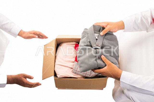 رجلان عربيان خليجيان سعوديان يتشاركان في تجهيز طرد الملابس للمحتاجين ، متطوعين لجمع التبرعات ، مشاريع وجمعيات خيرية ، عطاءات وتبرعات ، خدمة المجتمع السعودي المتعفف ، مؤسسة خيرية في المملكة العربية السعودية