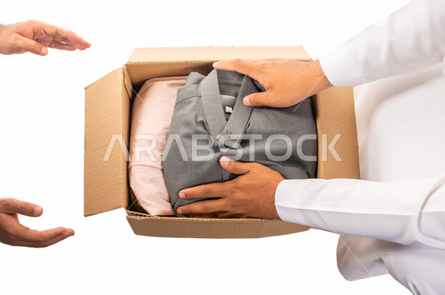 رجلان عربيان خليجيان سعوديان يتشاركان في تجهيز طرد الملابس للمحتاجين ، متطوعين لجمع التبرعات ، مشاريع وجمعيات خيرية ، عطاءات وتبرعات ، خدمة المجتمع السعودي المتعفف ، مؤسسة خيرية في المملكة العربية السعودية