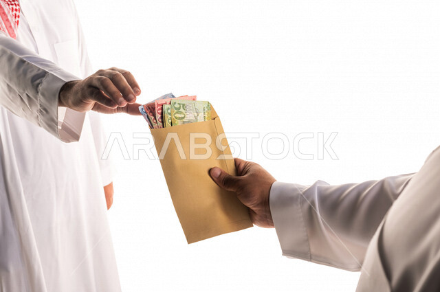 بورتريه لرجل عربي خليجي سعودي يقوم باعطاء ظرف النقود الورقية لرجل خليجي ، اخراج زكاة الفطر للمحتاجين ، الصدقة في شهر رمضان ، تقديم العيدية ، التكافل الاجتماعي ، العطاء والصدقة ، العبادة والتقرب الى الله 