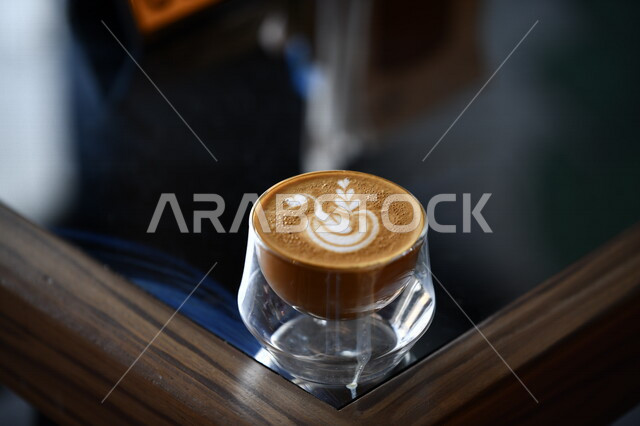 صورة لفنجان القهوة على الطاولة الزجاجية ، مشروب الكابتشينو بالرغوة ، مشروبات ساخنة ، كافيهات ومقاهي 