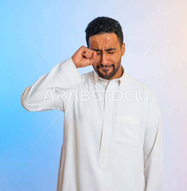 بورتريه لرجل عربي خليجي سعودي يقوم بفرك عينيه بايماءات تدل على الاستيقاظ من النوم ، آلام في العين ،  النعاس والارهاق ، الحاجة الى النوم 