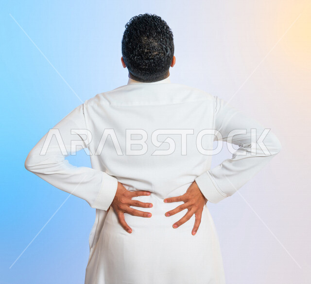 بورتريه من الخلف لرجل عربي سعودي خليجي يضع يديه على ظهره ، ايماءات تدل على آلام الظهر والعمود الفقري ، التعب والارهاق ، التشنج العضلي ، مشاكل صحية 