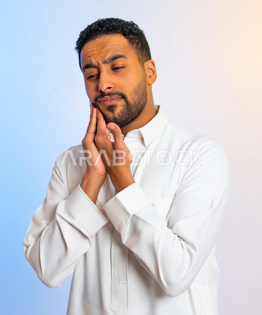 بورتريه لرجل عربي سعودي خليجي يضع يده على وجهه ، ايماءات وجه ويدين تدل على الم ووجع في الاضراس  ، تسوس الاسنان ، التهابات اللثة ، ألم الاسنان ، التهاب الفم