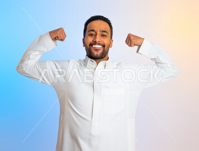 Portrait of a Saudi Arabian Gulf man displaying muscles, enjoying a healthy body, making hand gestures indicating strength and courage, healthy physique, physical fitness, muscles