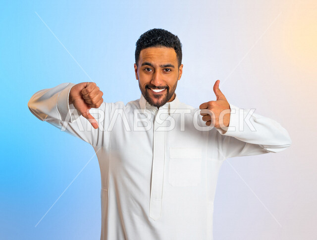 بورتريه لرجل عربي خليجي سعودي يقوم بايماءات يدين تدل على الموافقة وعدم الموافقة ، التردد في شيء ما ، الاعجاب وعدم الاعجاب ، تقييم سلبي وايجابي  للخدمات ،شاب يرفع اصبع الابهام لأعلى وأسفل 