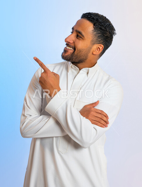 بورتريه لرجل عربي خليجي سعودي ومكتف اليدين، يشير باصبع السبابة الى هدف ما، حركة اصبع واشارات، ايماءات وتعابير الوجه تدل على الفرح والسعادة