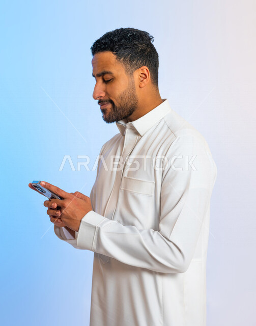 بورتريه لشاب عربي خليجي سعودي يقوم باستخدام الهاتف المحمول ، التواصل مع الأفراد ، طلبات أونلاين و تسويق ، علاقات اجتماعية ، دردشة و تعارف ، التواصل الإجتماعي ، استخدام أجهزة تقنية 